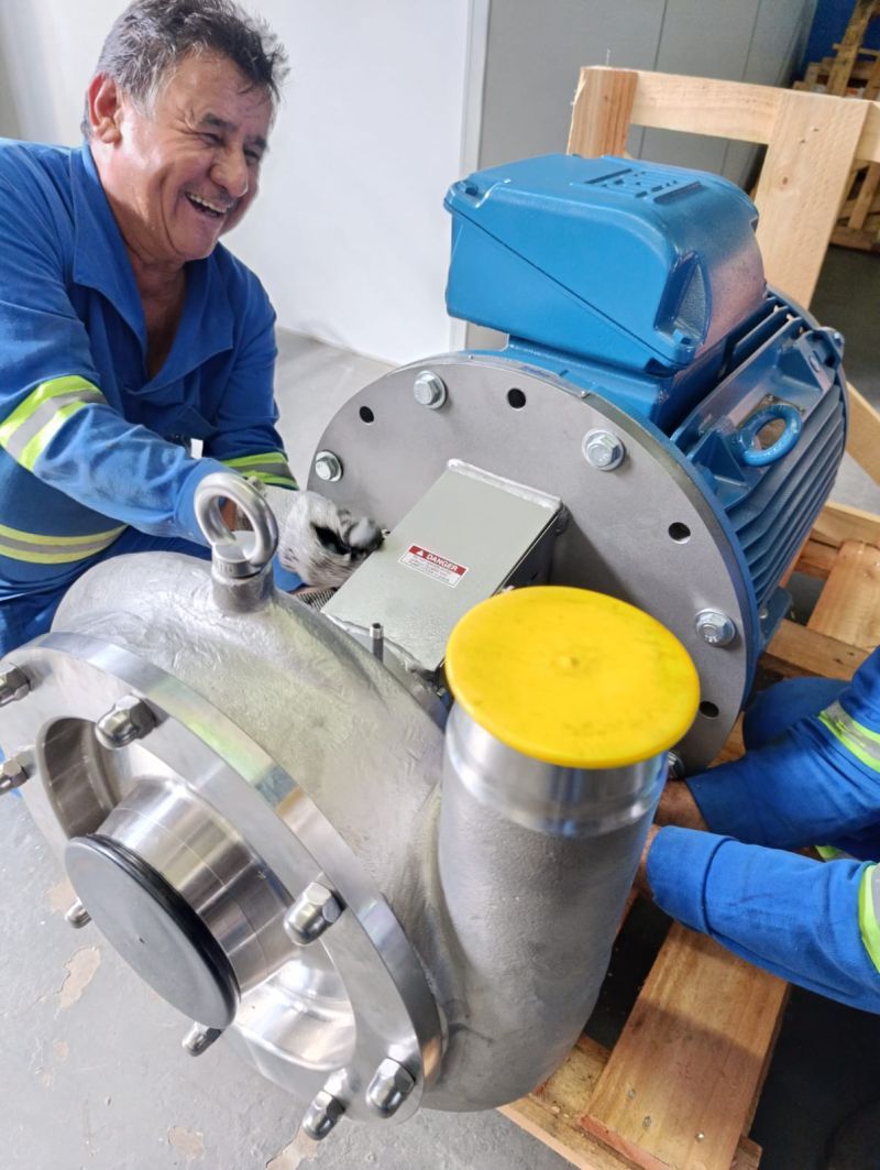 Mecânico da Futura sorrindo ao lado de uma bomba industrial em aço inox